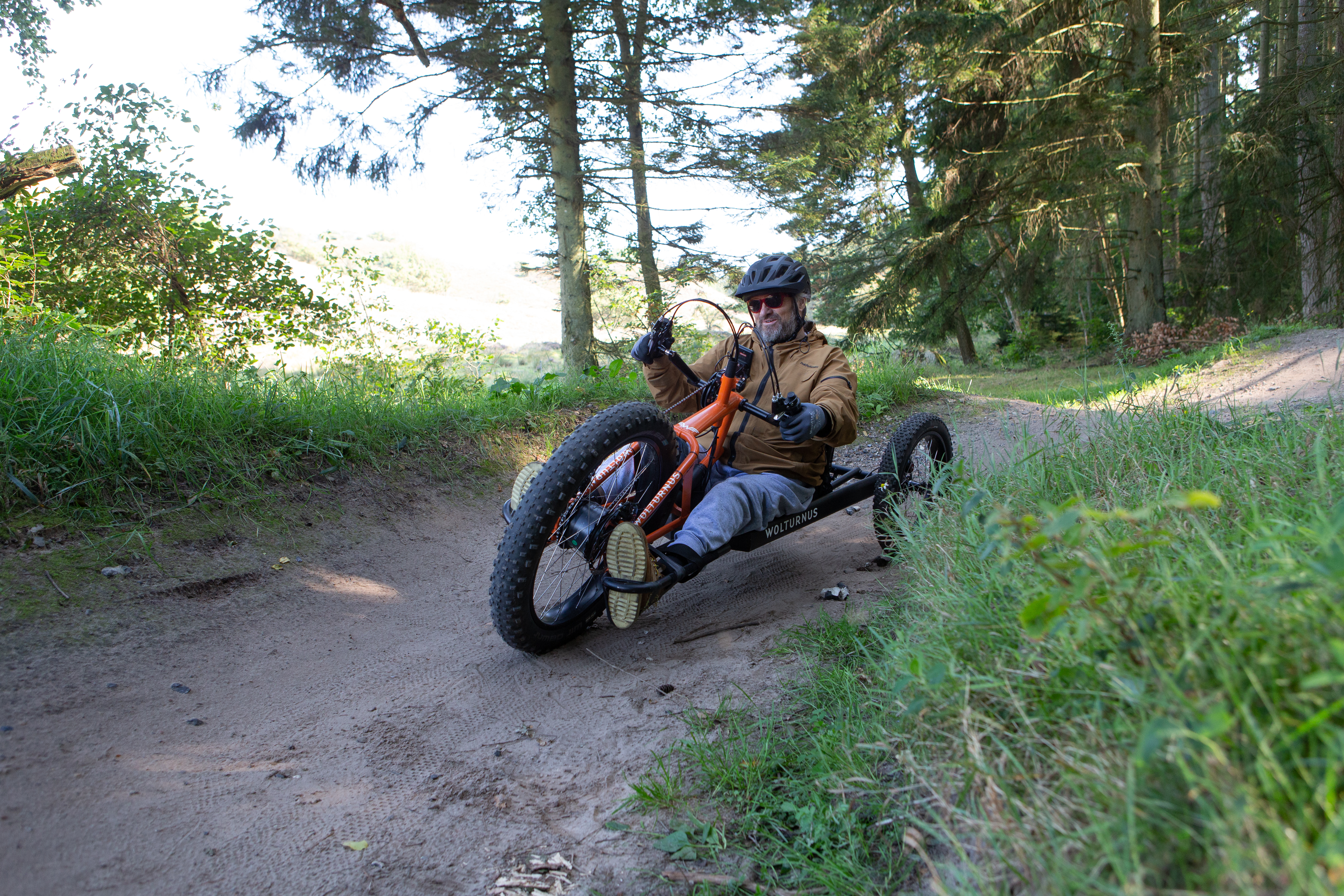 Fahrer auf dem Wolturnus Fatbike Offroad-Handbike auf einem Waldweg zwischen Bäumen