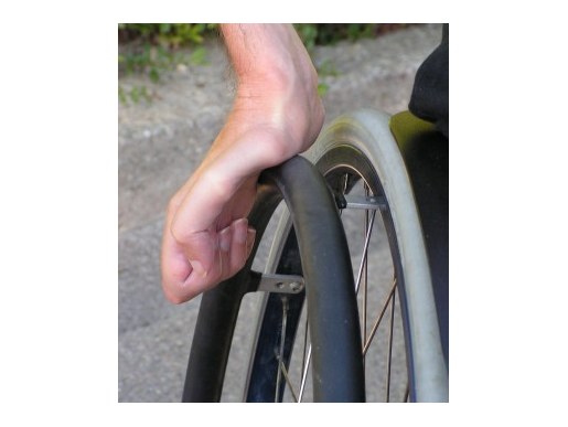 Hand auf einem Tetra-Gripp Greifreifen am Rollstuhlrad