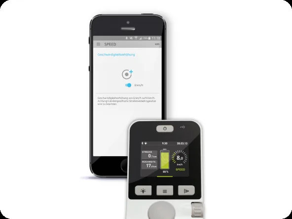 Smartphone-Bildschirm mit der Geschwindigkeitsanzeige des Alber e-fix neben dem Display des Bediengeräts