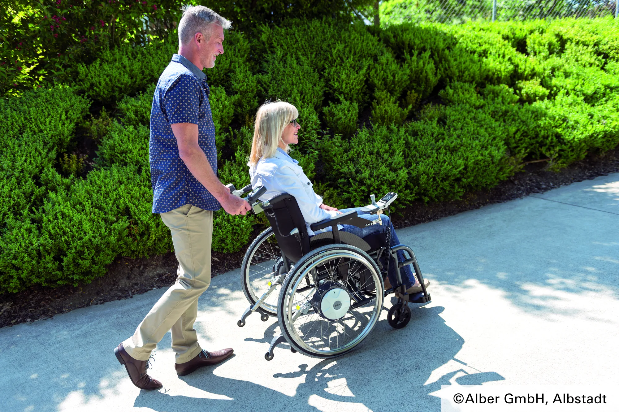 Rollstuhlfahrerin mit e-fix und Begleitperson im Park