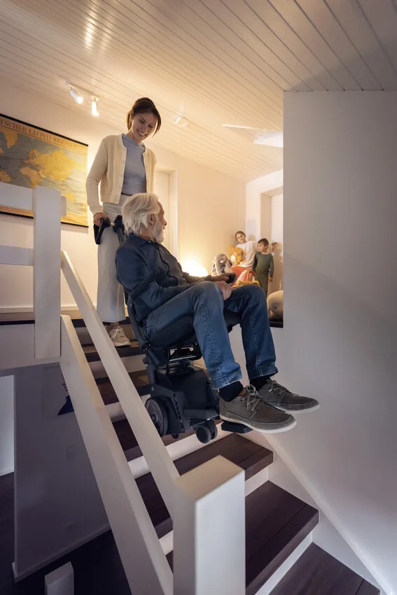 Begleitperson bringt eine sitzende Person mit dem Alber scalacombi S46 eine Treppe hinunter