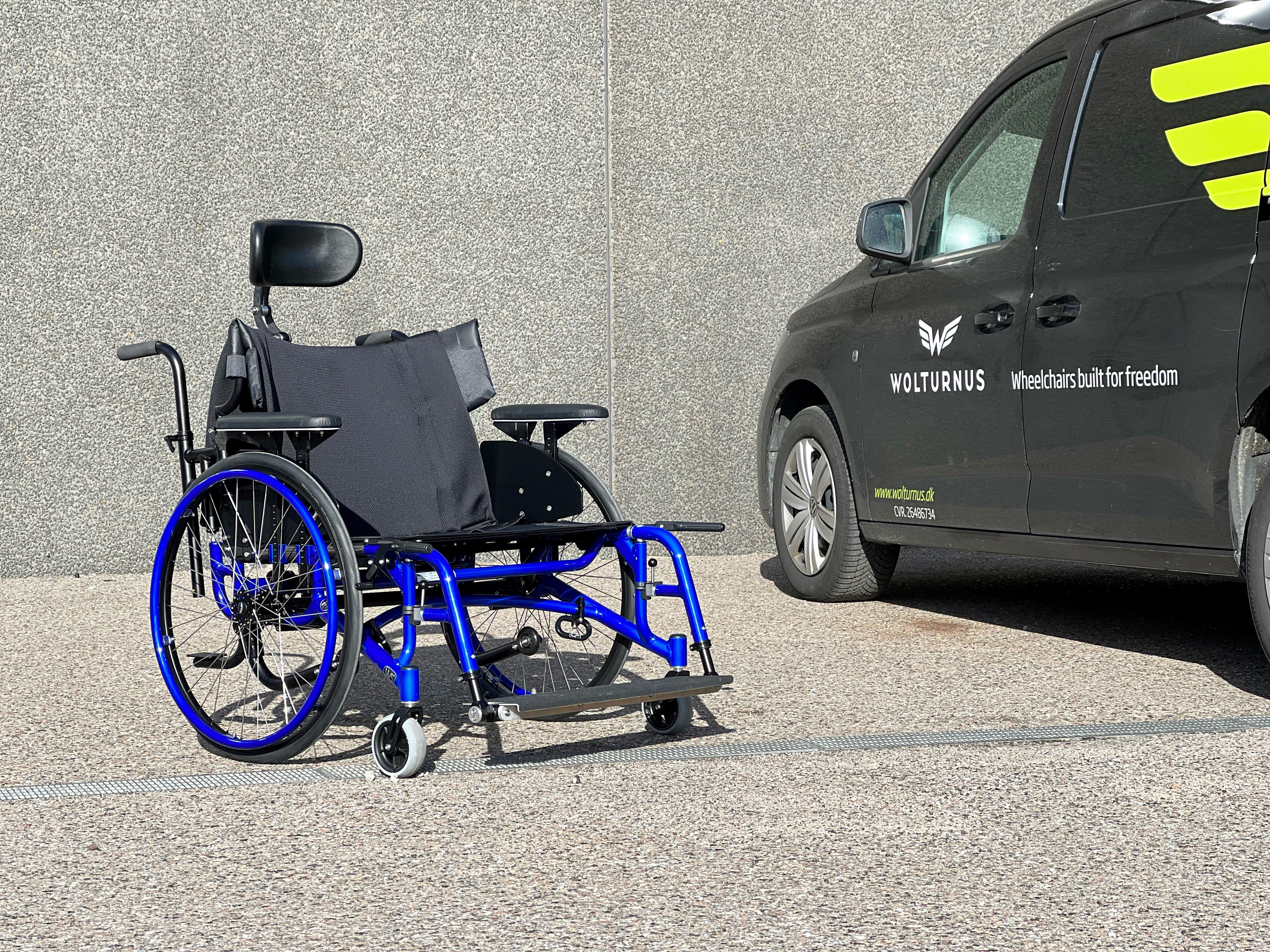 Wolturnus W5 XXL in Blau mit Kopfstütze und Kippschutz neben einem Fahrzeug