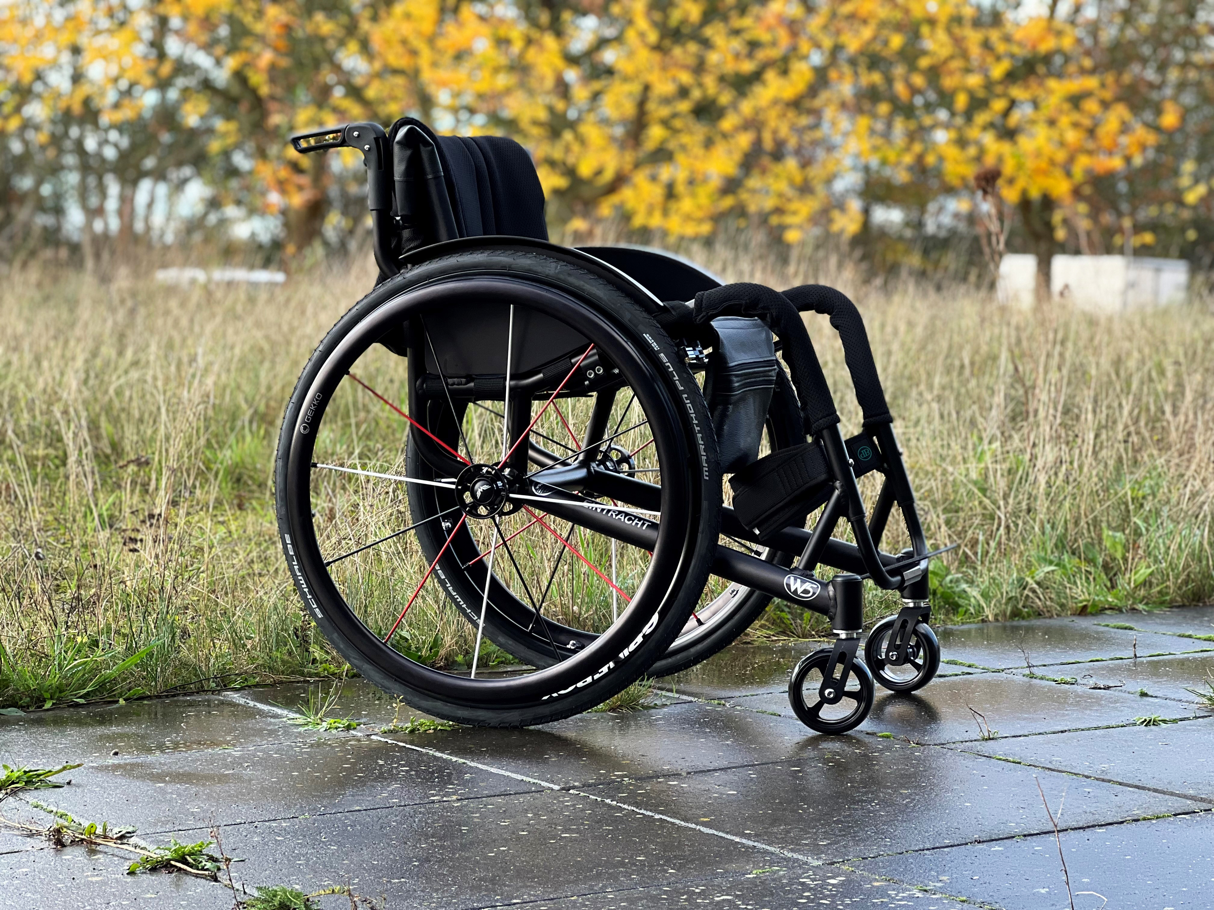 Wolturnus W5 K in Schwarz mit Froglegs-Lenkrädern und Spinergy-Rädern auf nassem Weg